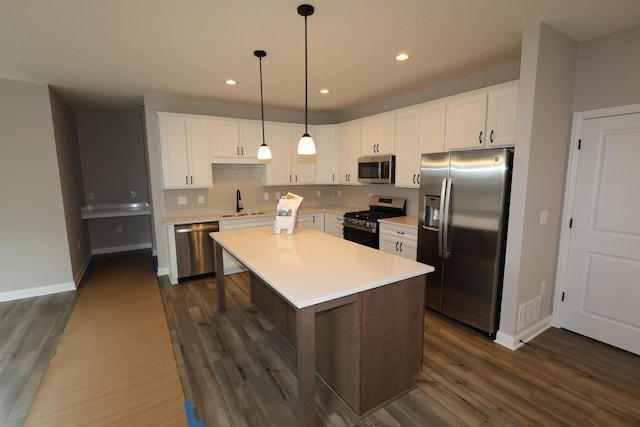 kitchen featuring dark wood-style floors, a sink, stainless steel appliances, light countertops, and white cabinetry