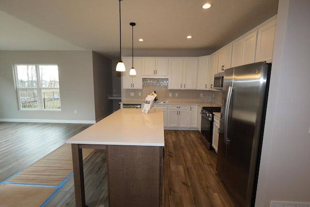 kitchen with dark wood finished floors, a center island, white cabinetry, appliances with stainless steel finishes, and decorative backsplash