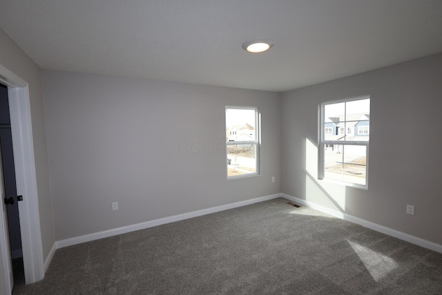 empty room featuring visible vents, baseboards, and carpet