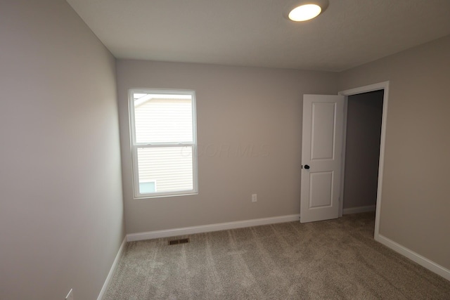 carpeted empty room featuring visible vents and baseboards