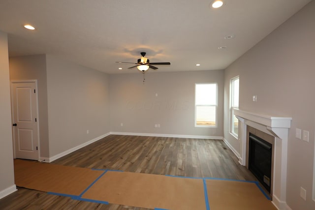 unfurnished living room featuring a tiled fireplace, wood finished floors, recessed lighting, baseboards, and ceiling fan