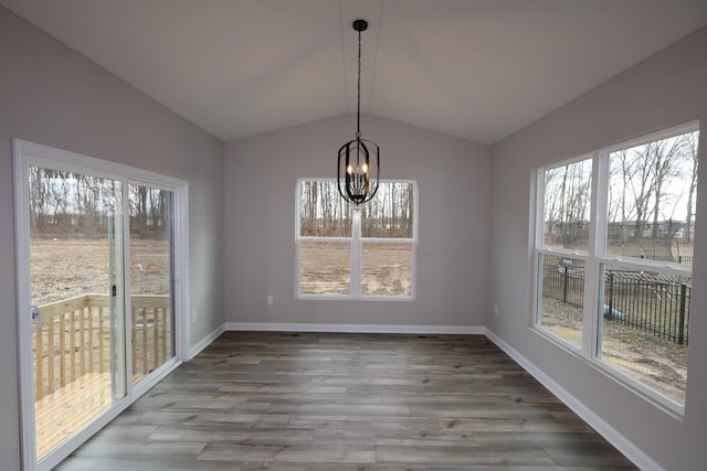 unfurnished dining area featuring baseboards, wood finished floors, an inviting chandelier, and vaulted ceiling