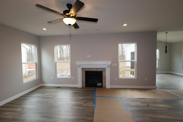 unfurnished living room featuring a ceiling fan, baseboards, recessed lighting, dark wood-style flooring, and a tile fireplace