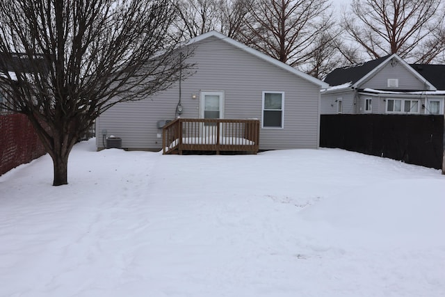 snow covered back of property with a wooden deck