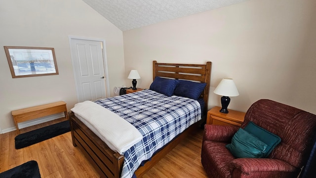 bedroom with a textured ceiling, light hardwood / wood-style flooring, and lofted ceiling