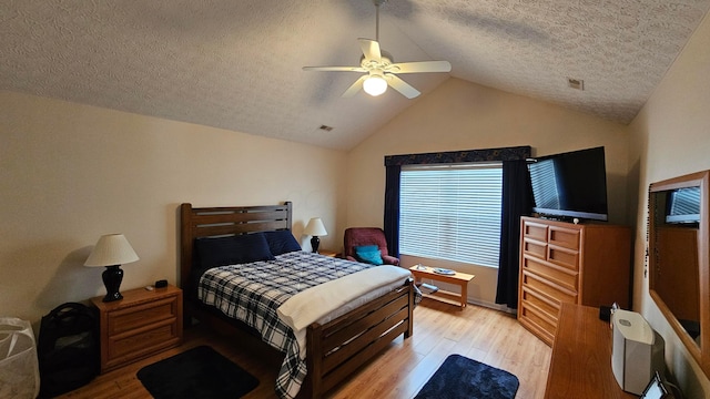 bedroom featuring ceiling fan, a textured ceiling, light wood-type flooring, and vaulted ceiling