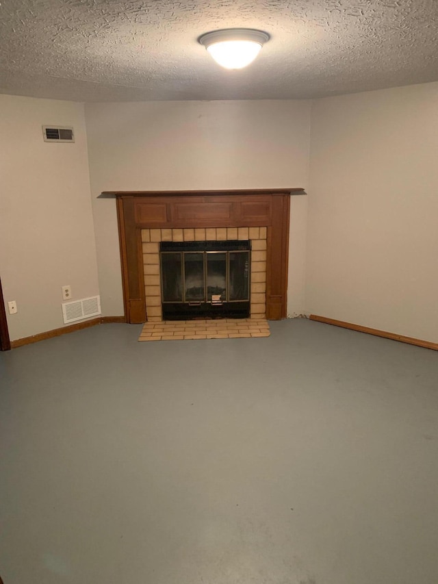 unfurnished living room featuring a textured ceiling and a brick fireplace