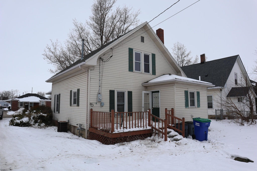 snow covered back of property featuring central air condition unit