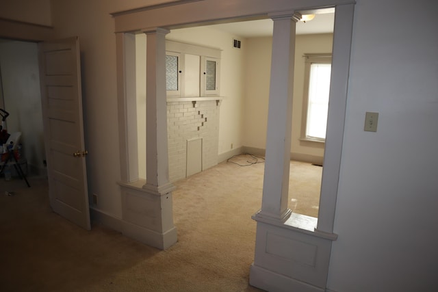 hallway with ornate columns and light carpet