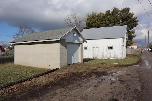 view of home's exterior with a garage, an outbuilding, and a lawn