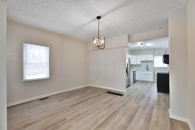 interior space featuring an inviting chandelier, light hardwood / wood-style floors, sink, and a textured ceiling