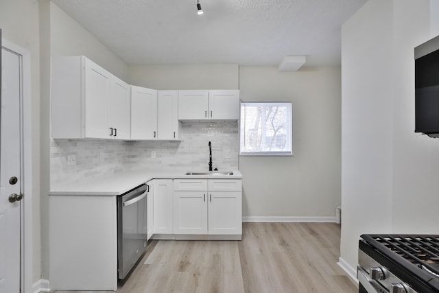 kitchen featuring sink, white cabinetry, light wood-type flooring, appliances with stainless steel finishes, and backsplash