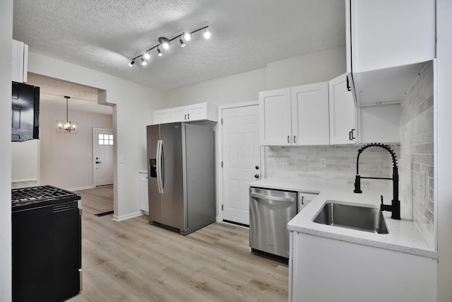 kitchen featuring appliances with stainless steel finishes, pendant lighting, white cabinetry, sink, and a textured ceiling