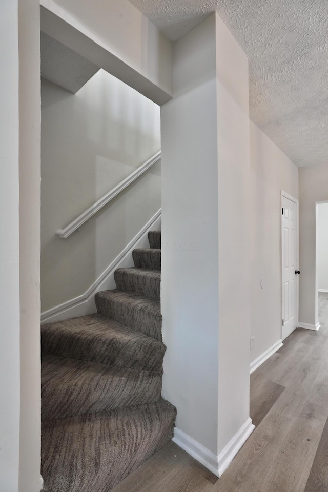 stairs with hardwood / wood-style flooring and a textured ceiling