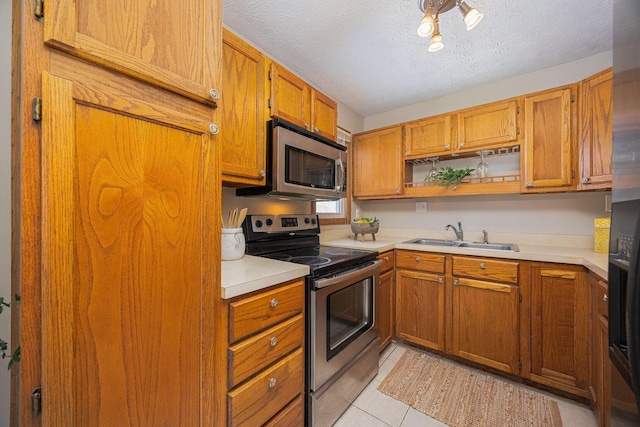 kitchen featuring sink, stainless steel appliances, a textured ceiling, and light tile patterned floors