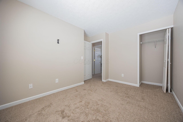 unfurnished bedroom featuring a textured ceiling, a closet, and light carpet