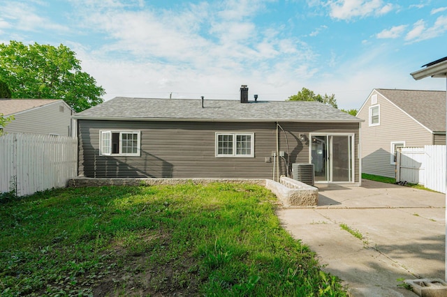 rear view of property featuring central AC unit, a lawn, and a patio area