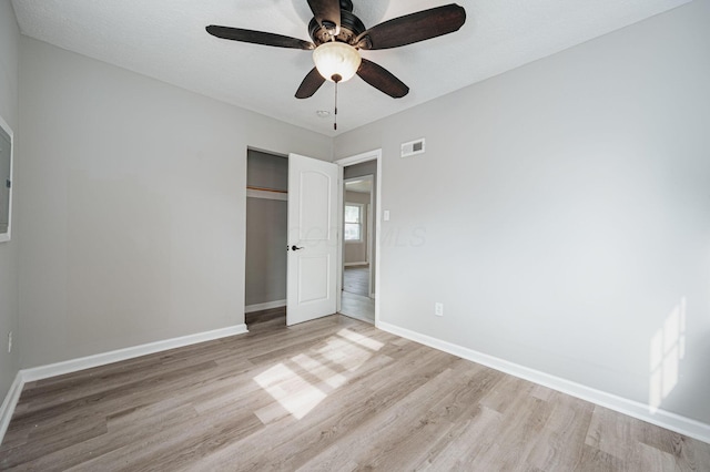 unfurnished bedroom featuring ceiling fan, light hardwood / wood-style flooring, and a closet