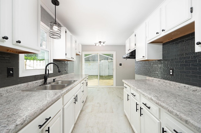 kitchen featuring sink, a healthy amount of sunlight, white cabinetry, and decorative light fixtures