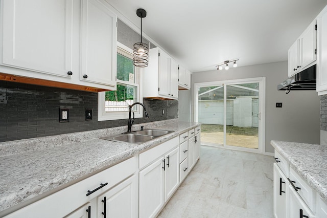 kitchen featuring sink, a healthy amount of sunlight, white cabinetry, and decorative light fixtures