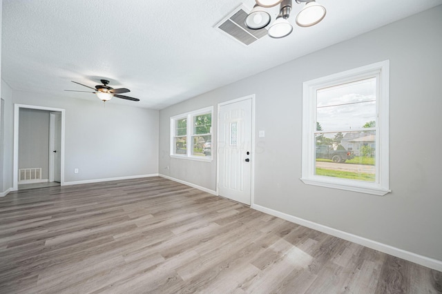 entryway with ceiling fan with notable chandelier, a textured ceiling, and light hardwood / wood-style floors