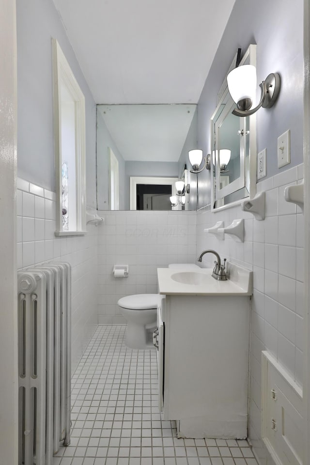 bathroom featuring tile patterned flooring, tile walls, radiator heating unit, vanity, and toilet