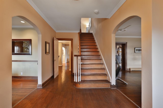 staircase featuring wood-type flooring, crown molding, and baseboard heating