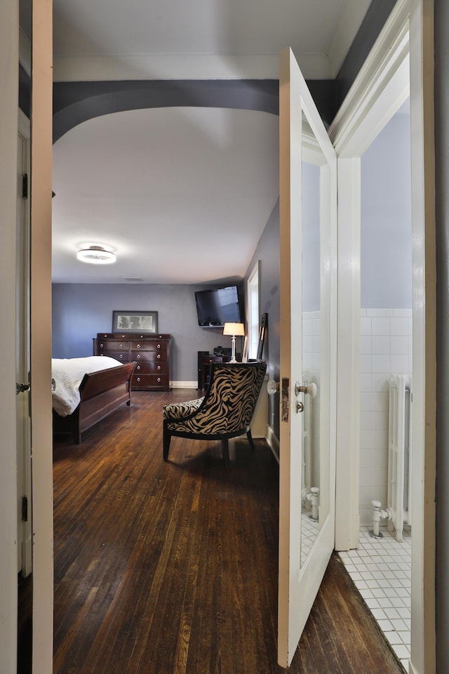 bedroom featuring tile walls, radiator heating unit, and wood-type flooring