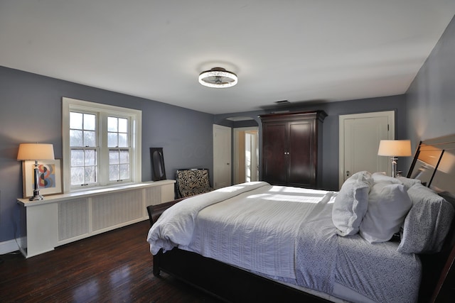 bedroom featuring radiator heating unit and dark hardwood / wood-style flooring