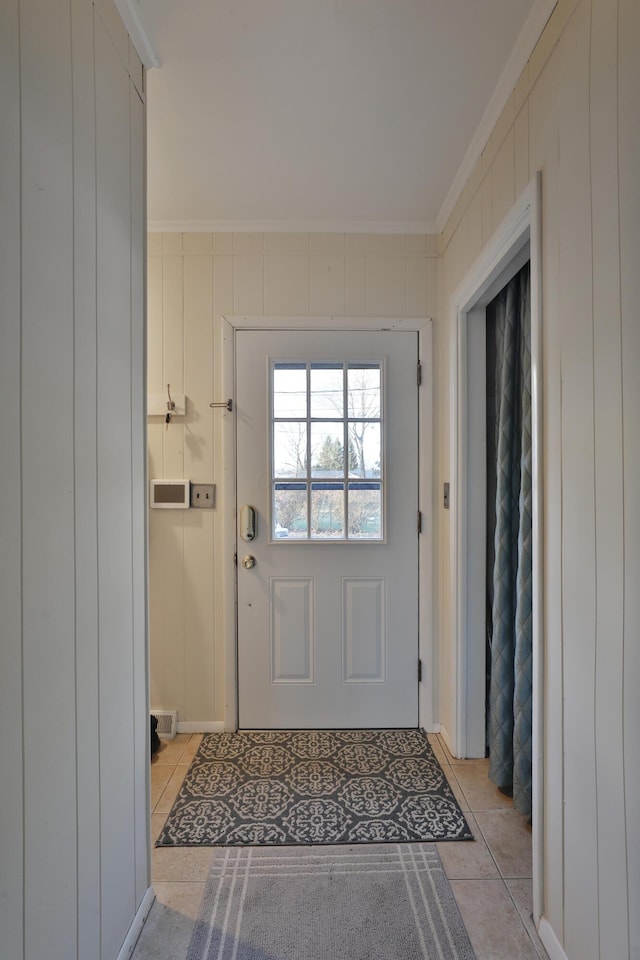 doorway featuring ornamental molding and light tile patterned floors