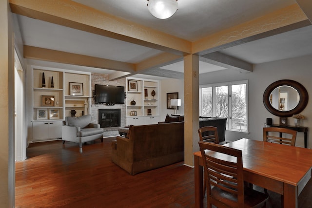 dining room featuring beamed ceiling, a brick fireplace, and hardwood / wood-style floors