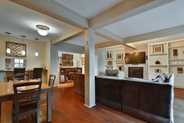 living room featuring beam ceiling, hardwood / wood-style floors, and a brick fireplace