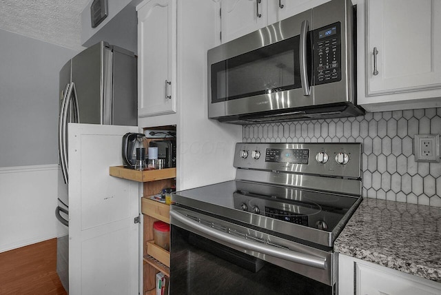 kitchen with stone counters, a textured ceiling, tasteful backsplash, white cabinets, and stainless steel appliances