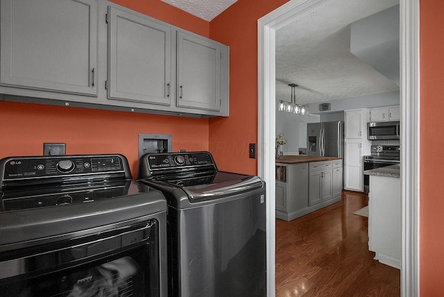 laundry room featuring cabinets, a textured ceiling, dark hardwood / wood-style flooring, and washing machine and dryer