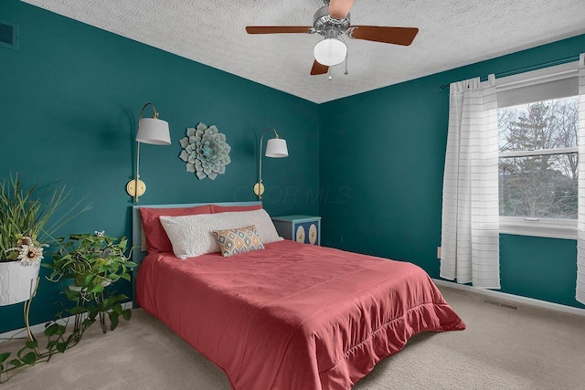 carpeted bedroom with ceiling fan and a textured ceiling