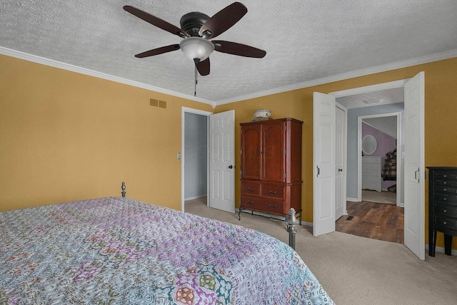 bedroom with ceiling fan, crown molding, light carpet, and a textured ceiling