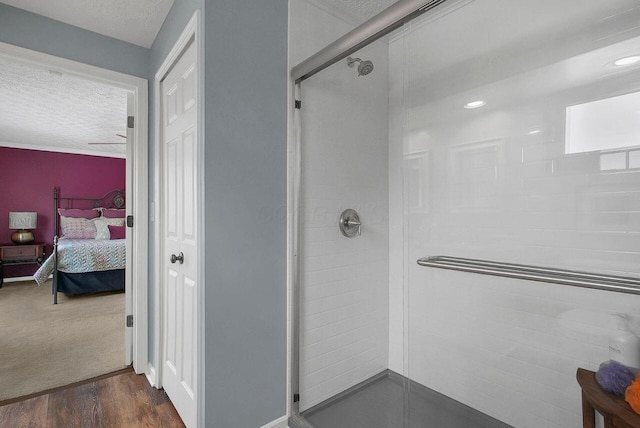 bathroom with hardwood / wood-style flooring, a textured ceiling, and a shower with door