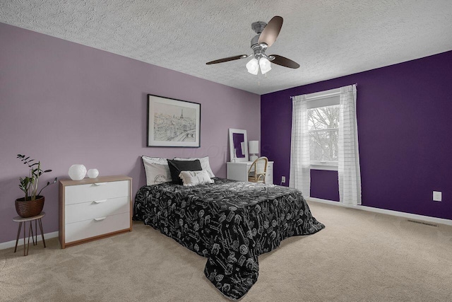 carpeted bedroom with ceiling fan and a textured ceiling