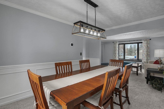 carpeted dining space with ornamental molding and a textured ceiling