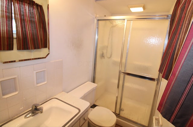 bathroom with an enclosed shower, sink, toilet, and tasteful backsplash