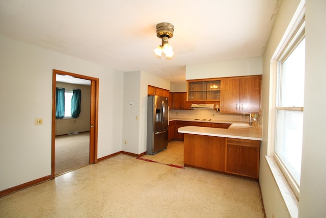 kitchen featuring stainless steel fridge with ice dispenser, kitchen peninsula, backsplash, range hood, and sink