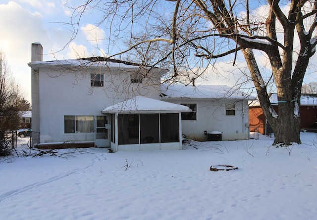 snow covered house featuring cooling unit and a sunroom