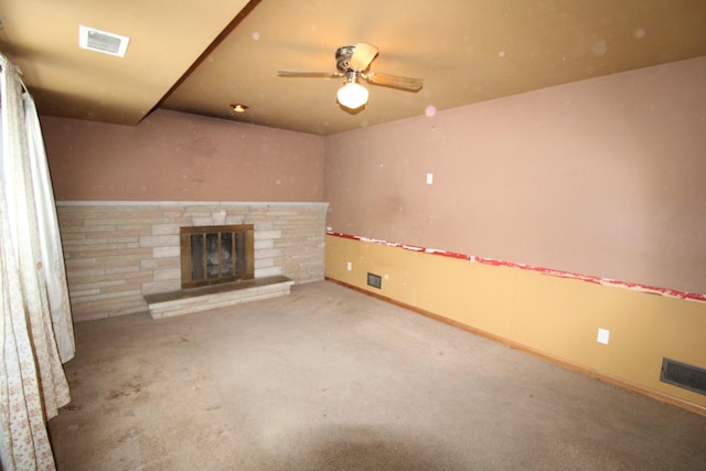 unfurnished living room featuring carpet floors, ceiling fan, and a stone fireplace