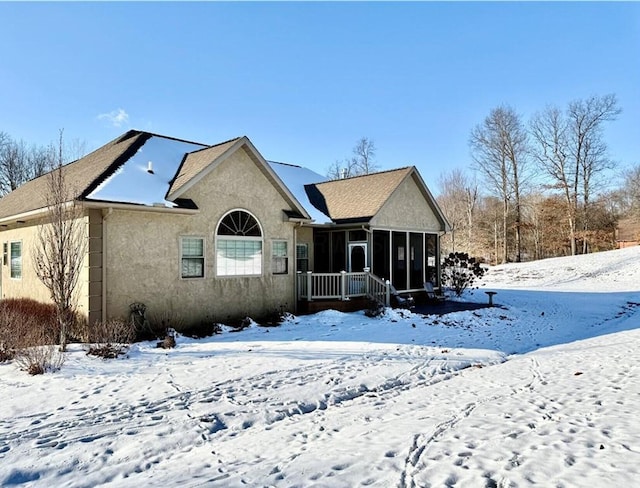 snow covered house featuring a sunroom