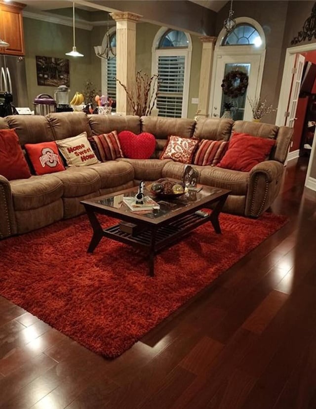 living area featuring decorative columns, dark wood finished floors, and ornamental molding