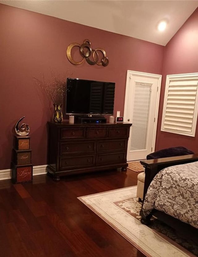 bedroom with dark wood-style floors, baseboards, and lofted ceiling