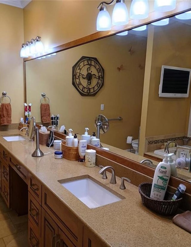 bathroom with a sink, toilet, double vanity, and tile patterned floors