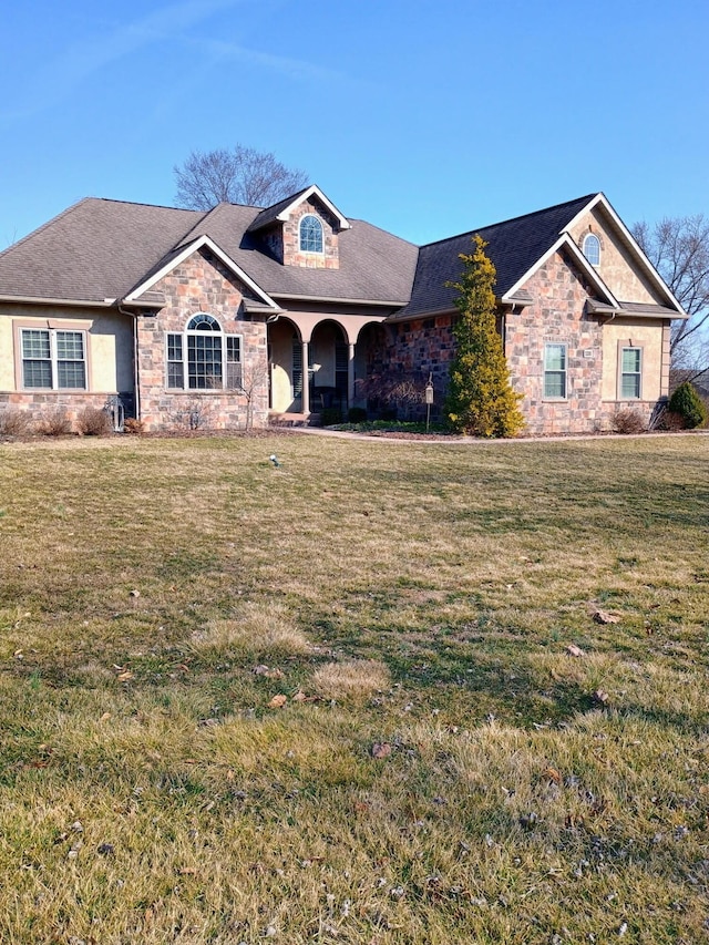 view of front of home featuring stone siding, a porch, and a front yard