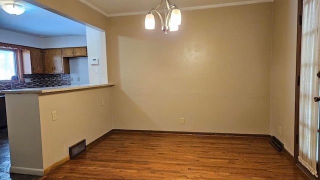 unfurnished dining area featuring dark hardwood / wood-style flooring, an inviting chandelier, and crown molding