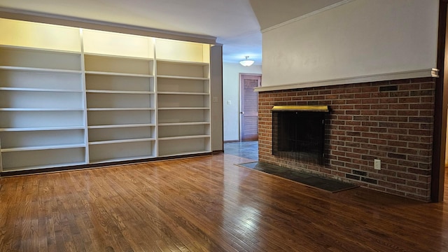 unfurnished living room with a fireplace, built in shelves, and hardwood / wood-style flooring